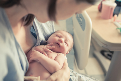 Newborn baby and mother in a hospital bed