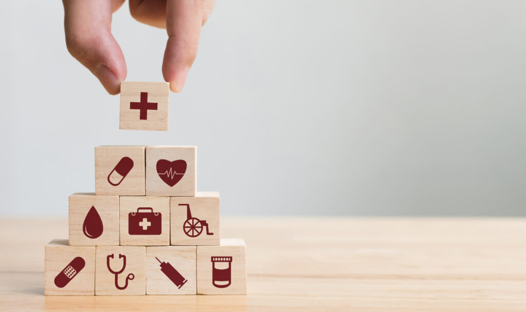 Hand arranging a stack of wooden blocks with medical icons on 