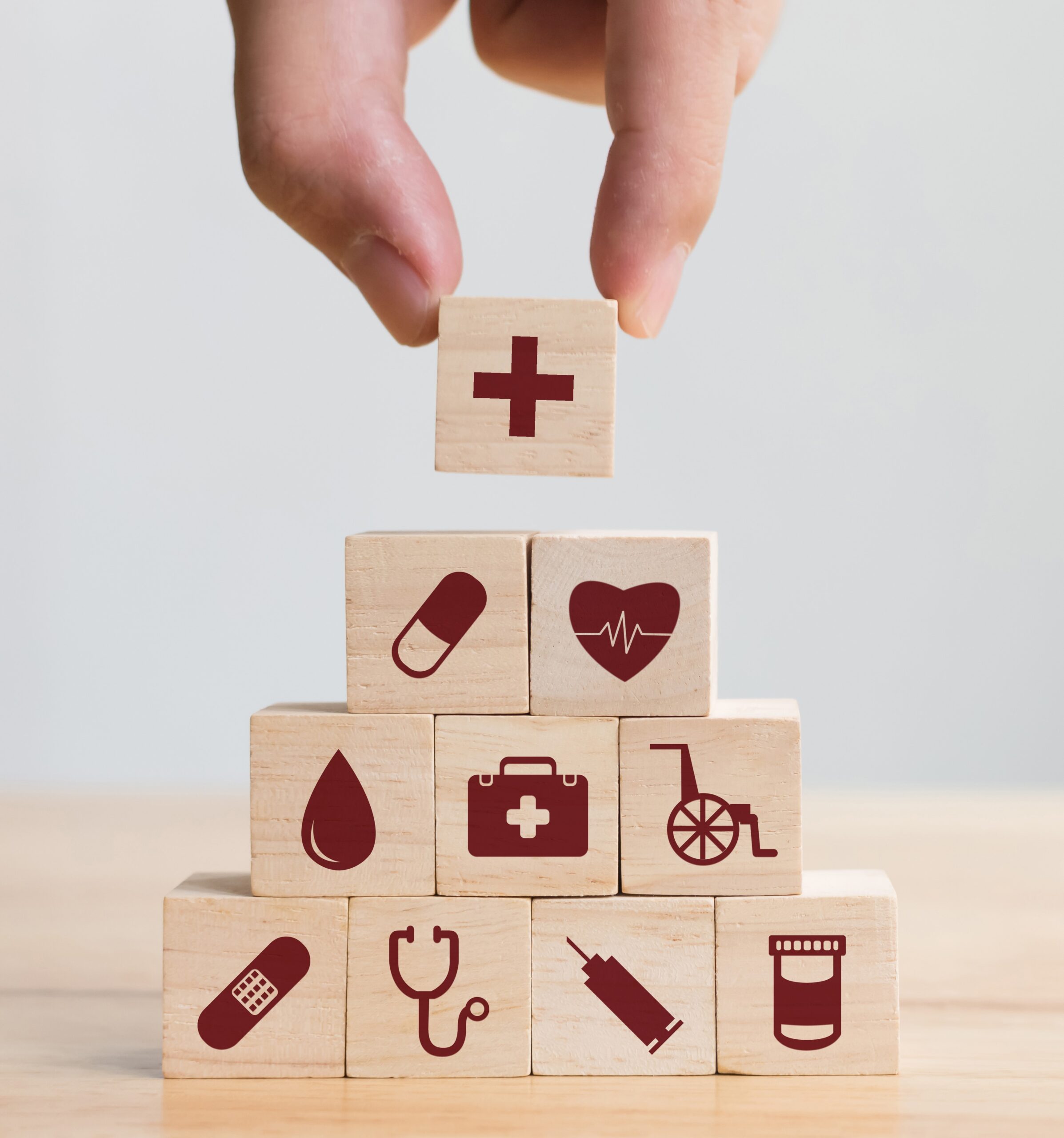 Hand arranging a stack of wooden blocks with medical icons on